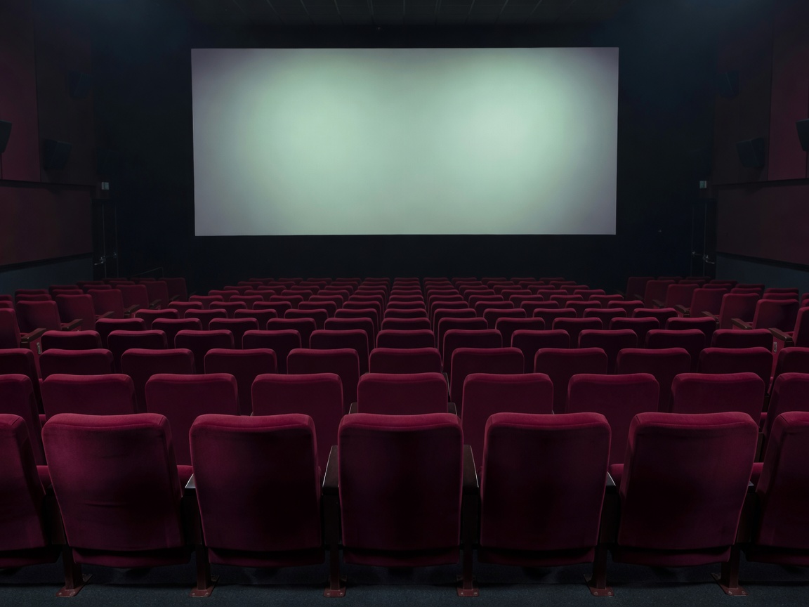 Empty screening-room seats facing a softly illuminated cinema screen
